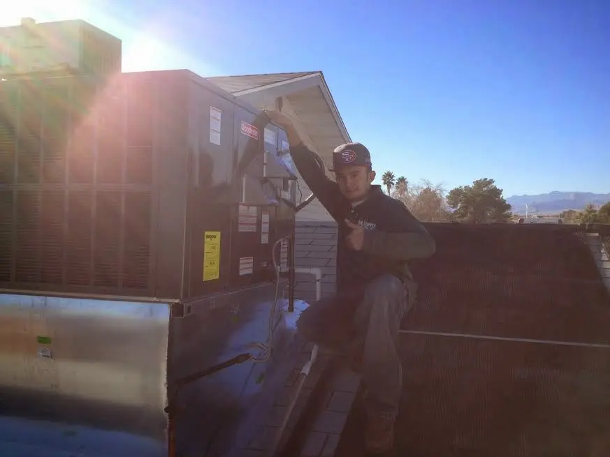 HVAC technician performing Air Duct Cleaning on a rooftop unit in Avon
